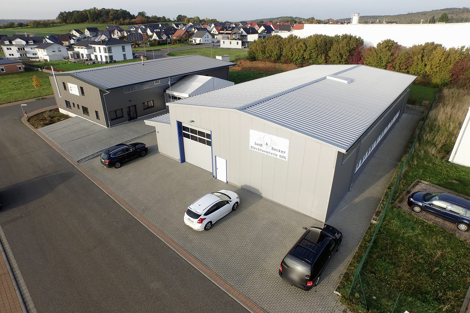 Luftbild zweier Gewerbehallen mit Rolltor, Büroeingang und Parkplätzen